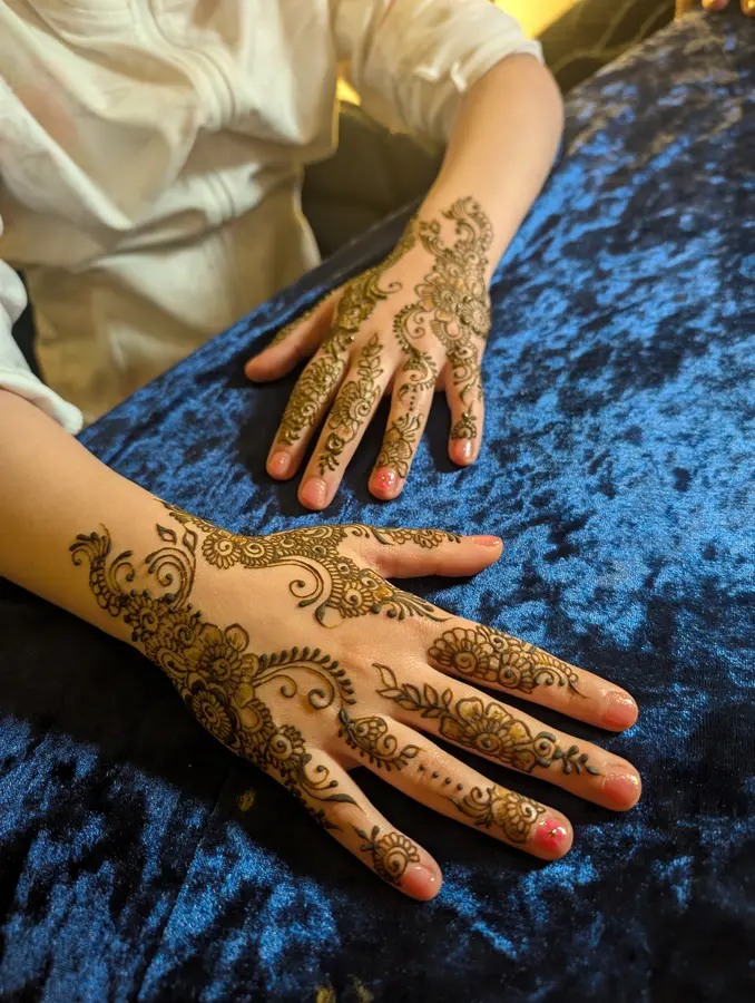 Karwa Chauth mehndi design across the backs of both hands, a trailing floral vine