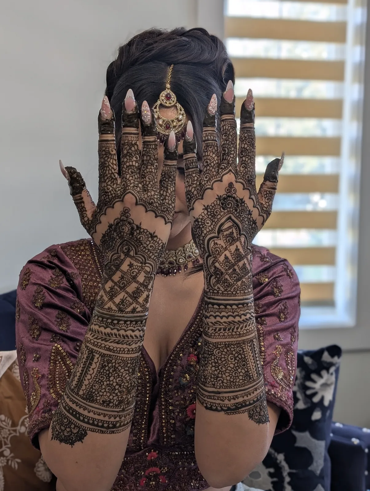 A bride holding up both hands to show her finished mehndi at her mehndi night