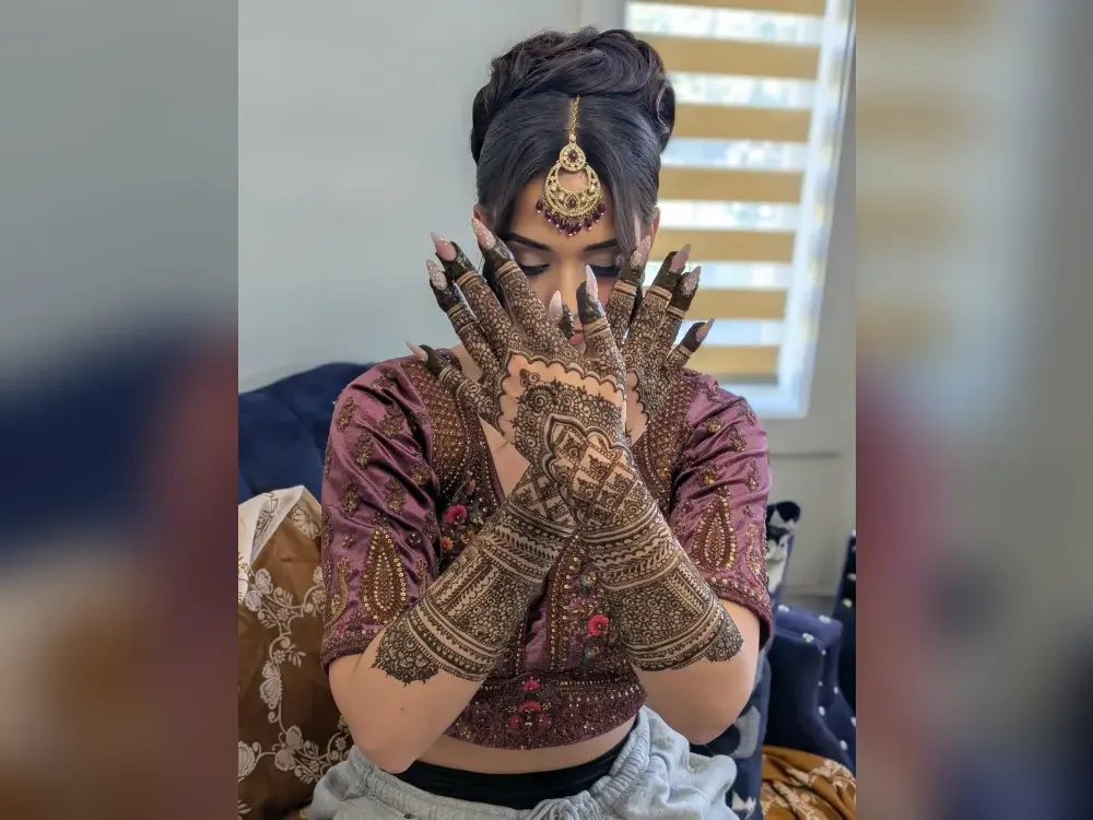 A Calgary bride holding up both hands to show her finished bridal mehndi
