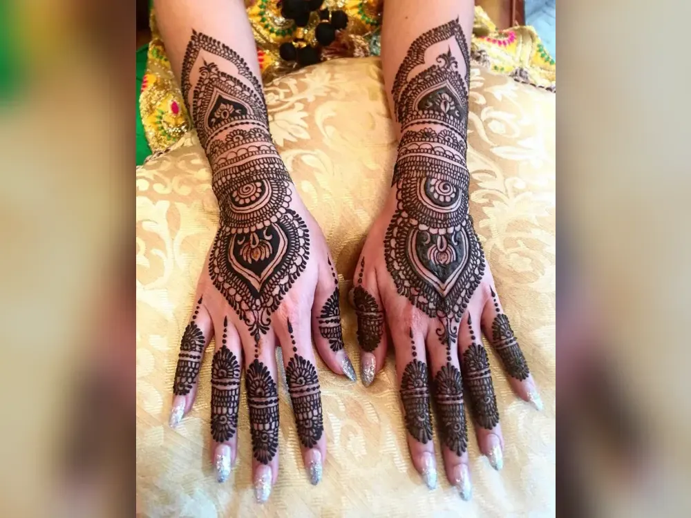 Dense bridal-style mehndi covering both hands and forearms, photographed after a Calgary appointment