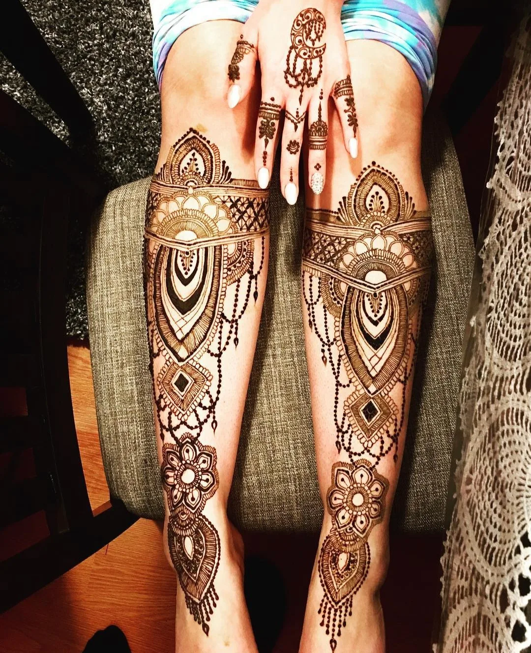 Bride in red bridal wear with henna on her hands during application