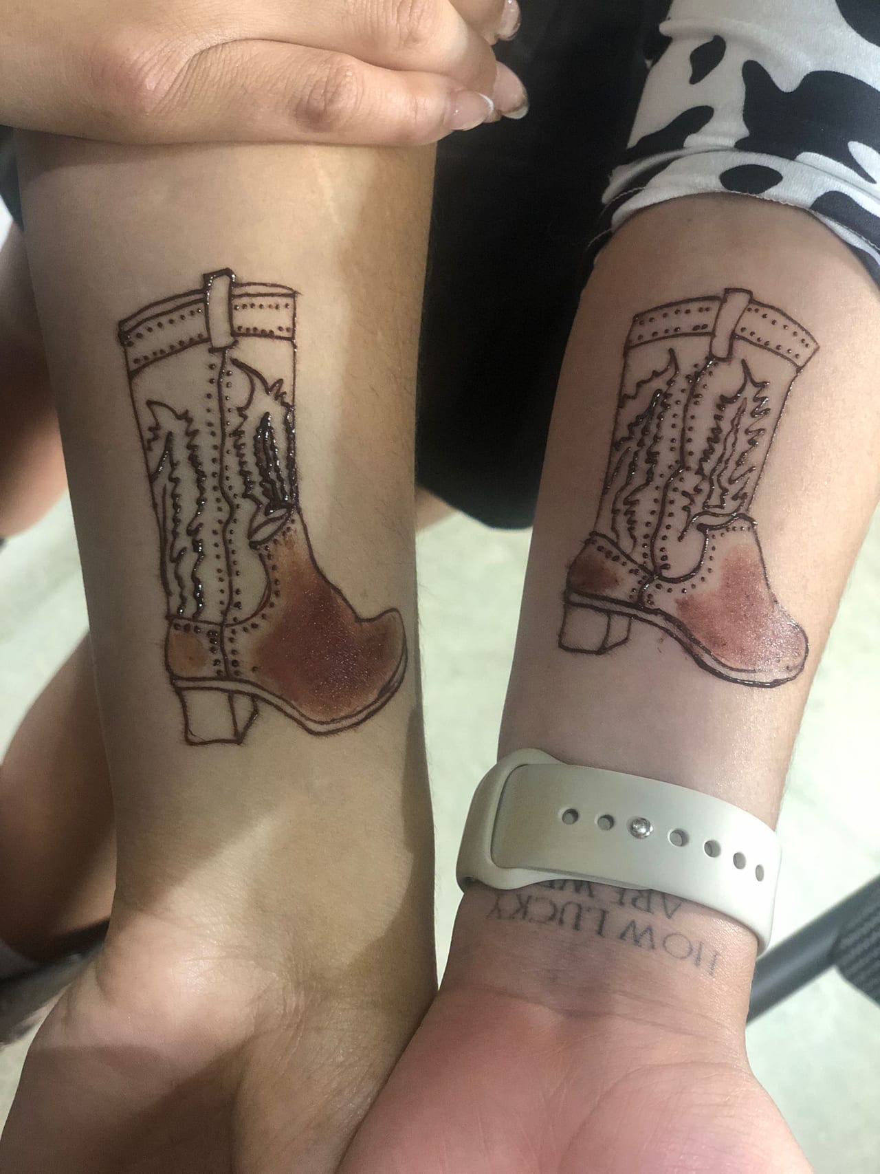 Matching cowboy boot henna tattoos on two friends' forearms, Calgary Stampede style