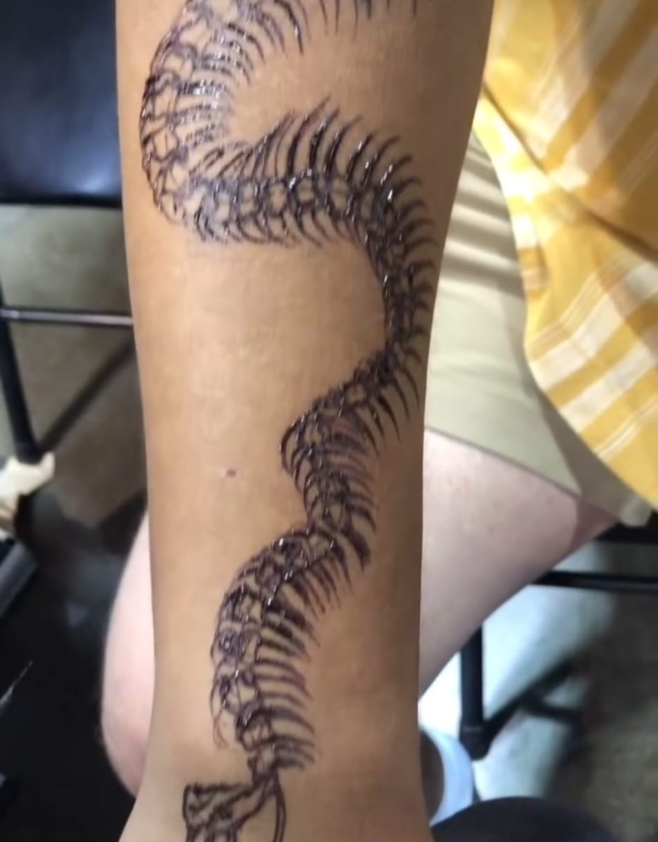 Serpent spine henna tattoo running down the leg in fine black freehand, Calgary