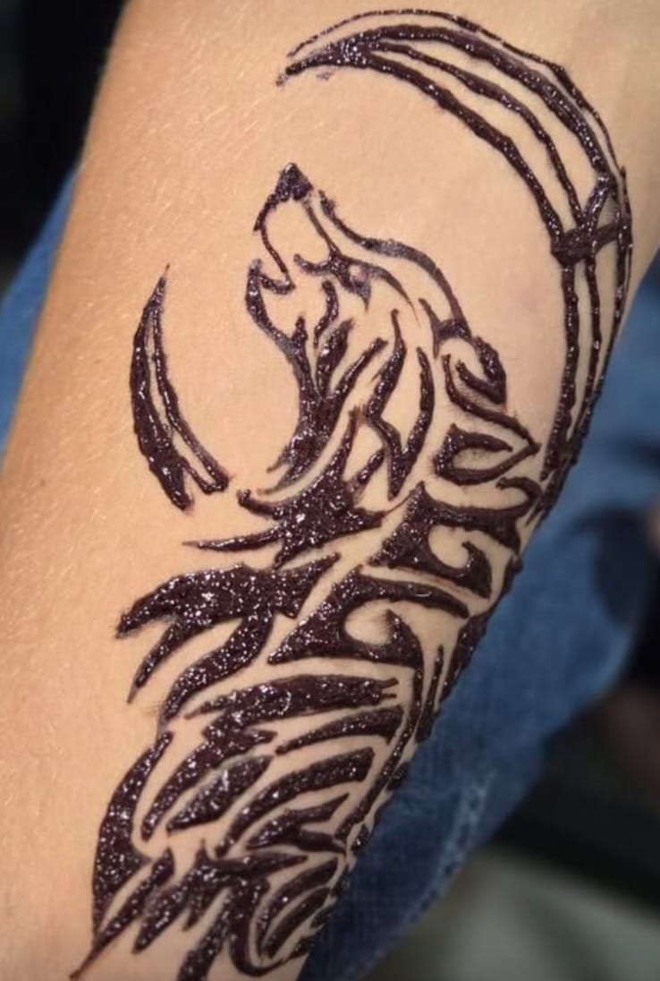 Tribal howling wolf and moon henna tattoo on a forearm in bold black with glitter, Calgary